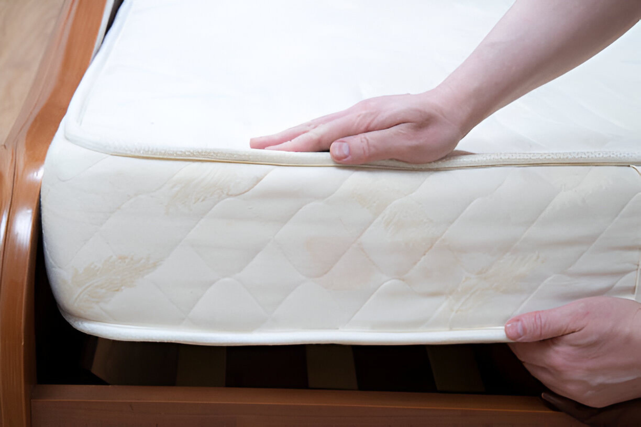 Here, a man is hand-checking whether a white mattress is perfect for his sleeping style.