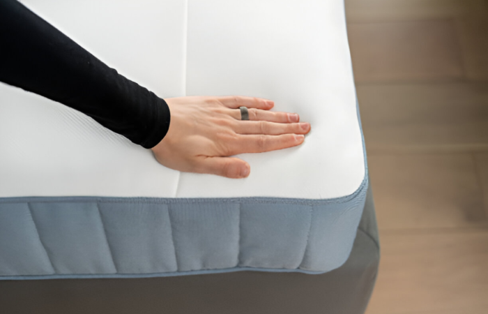 Here, a girl is comparing latex vs memory foam mattresses with her hands on a white mattress.