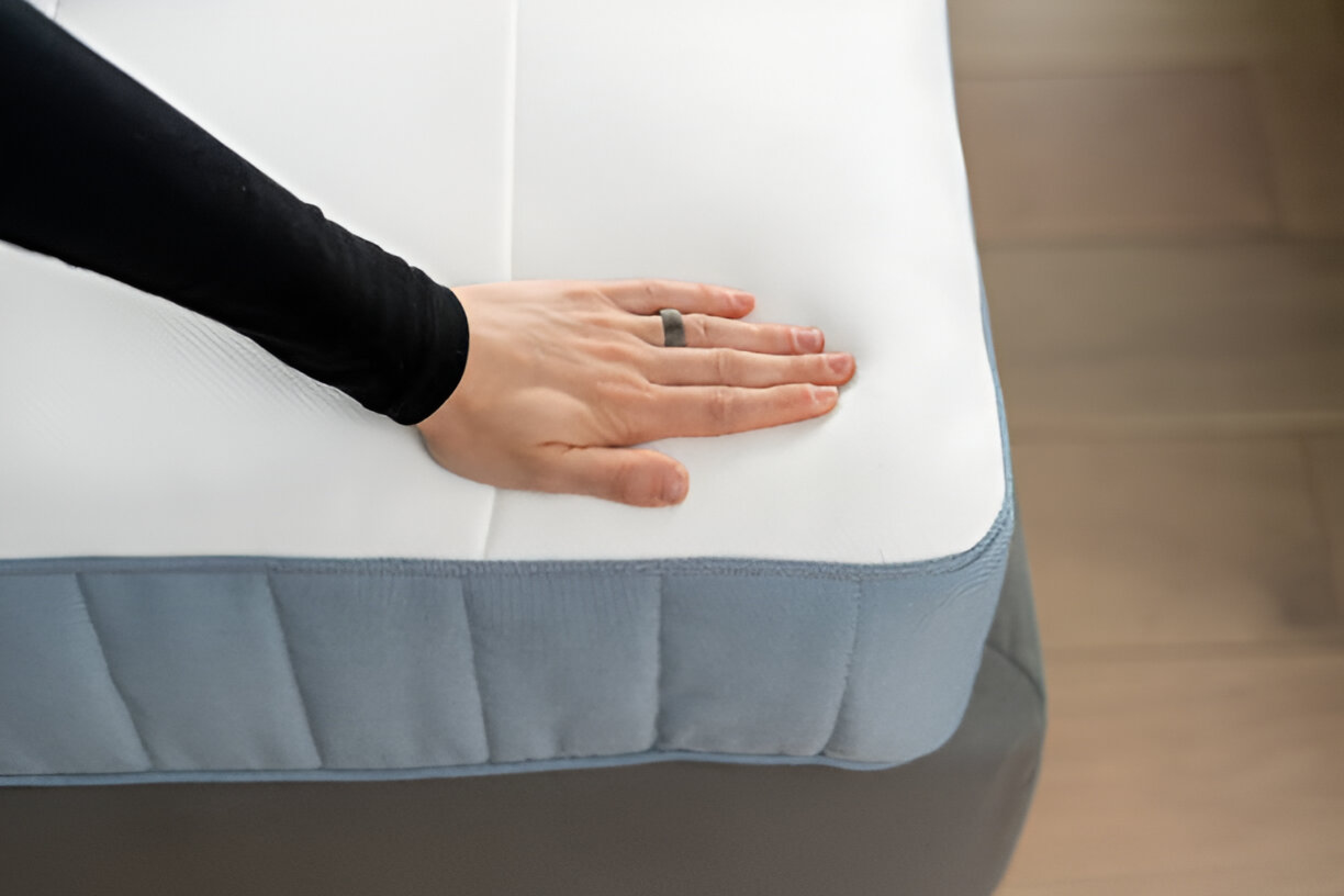 Here, a girl is comparing latex vs memory foam mattresses with her hands on a white mattress.