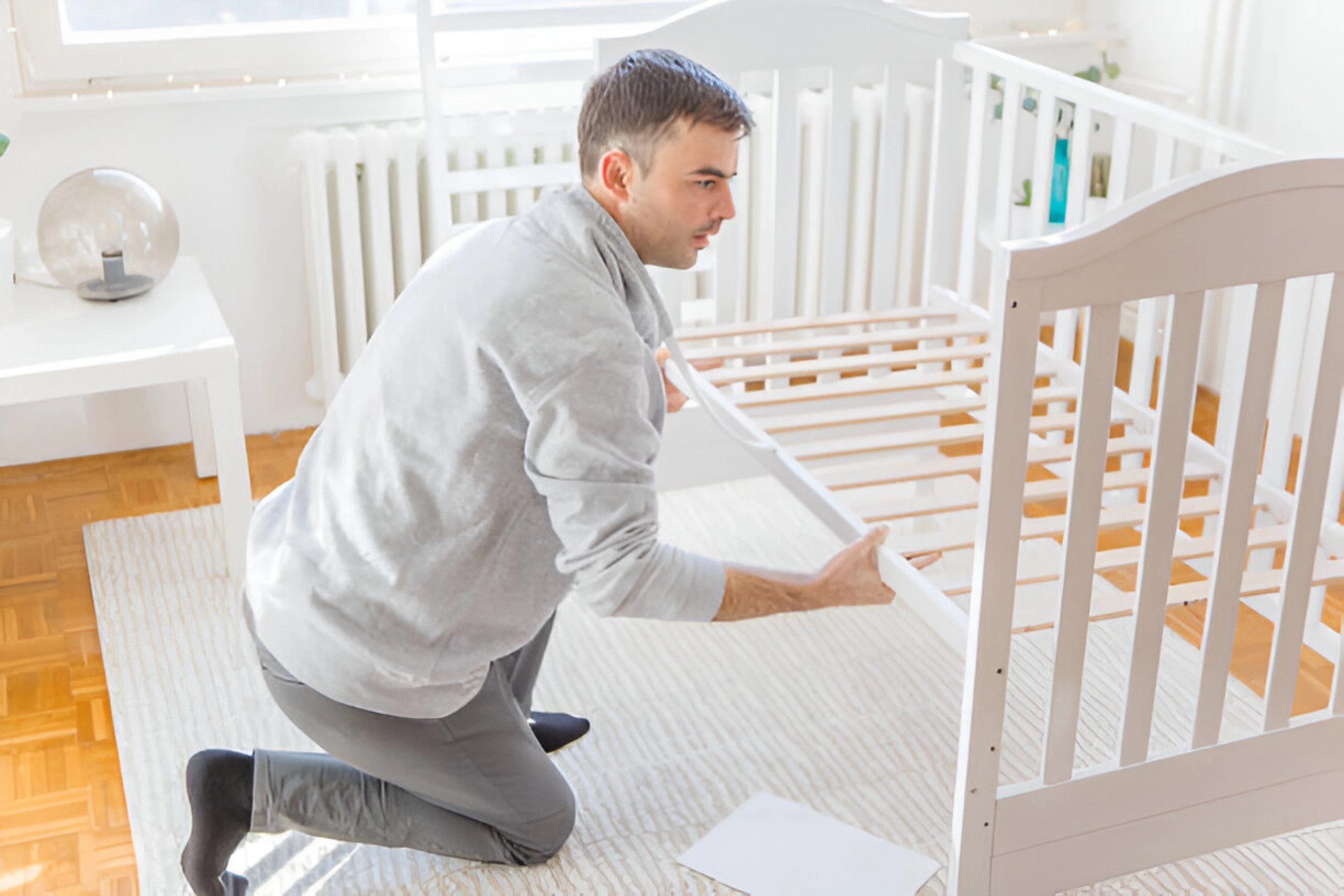 Here is a person setting up white color cribs step by step.