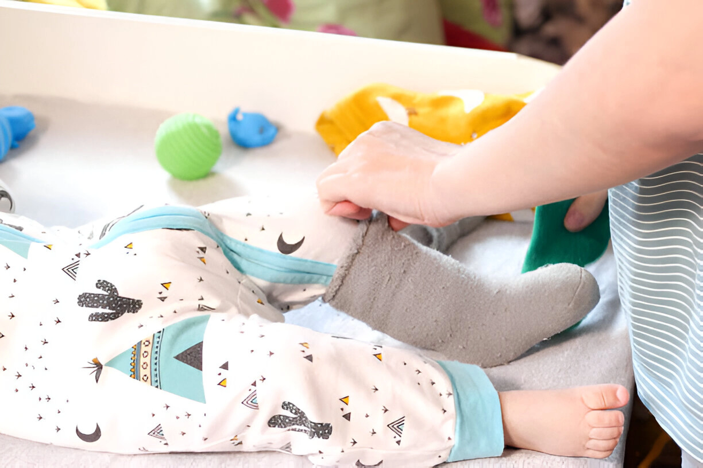Here is a mother putting her baby in a sleep sack.